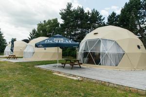 a row of tents with a picnic table in the grass at Glamping Prague Louka in Prague