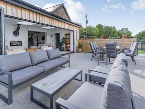 a patio with a couch and tables and chairs at Y Gelli in Pont Yates