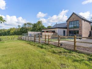 a house with a wooden fence in front of a field at Y Gelli in Pont Yates