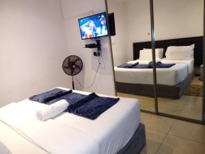 a bedroom with two beds and a tv on the wall at Lancaster Guest House in Boksburg
