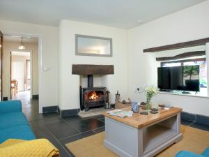 a living room with a fireplace and a blue couch at Uk45541-Old Stable Cottage in Sticklepath