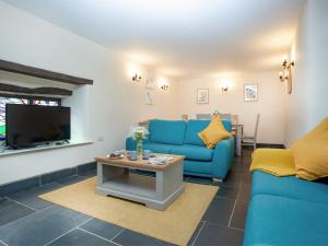 a living room with blue couches and a tv at Uk45541-Old Stable Cottage in Sticklepath