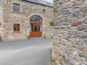 a stone house with a wooden door and a driveway at Warth Barn - Uk44211 in Ingleton