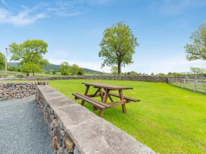 a picnic table in a field with a stone wall at Warth Barn - Uk44211 in Ingleton