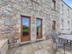 a patio with a table and chairs in front of a stone building at Warth Barn - Uk44211 in Ingleton