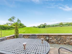 a table and chairs on a patio with a stone wall at Warth Barn - Uk44211 in Ingleton
