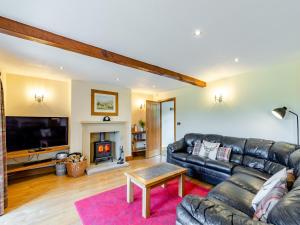 a living room with a leather couch and a fireplace at Warth Barn - Uk44211 in Ingleton +26 photos