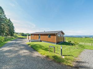 a house on a gravel road next to a field at Glencoe Luxury Lodge in Erskine