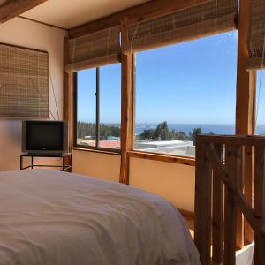 um quarto com uma cama e uma grande janela em Cabañas Pichilemu Casa Verde em Pichilemu