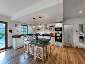 a kitchen with white appliances and a table with stools at Pant Ifan Goch in St Asaph