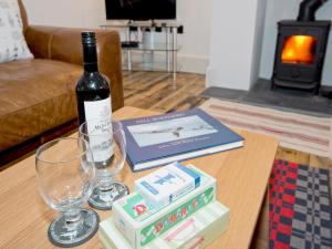 a bottle of wine and some books on a table at Ty Cai in Llanwnda