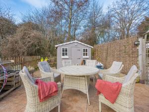 a patio with a table and chairs and a shed at Amaranth in Shurdington