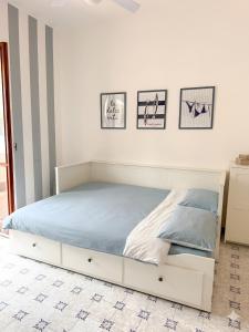 a white bed in a white bedroom with pictures on the wall at VitaDaMare in Giardini Naxos