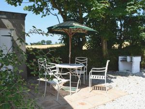 a table and chairs under an umbrella on a patio at Blackberry Cottage in North Hill +7 photos