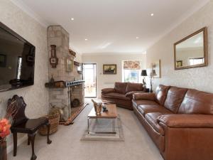 a living room with a leather couch and a fireplace at Hillend Farm House in Dalry