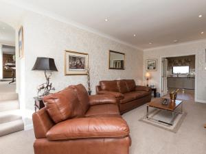 a living room with a leather couch and a table at Hillend Farm House in Dalry