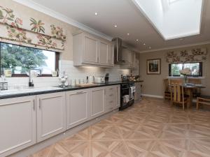 a large kitchen with white cabinets and a table at Hillend Farm House in Dalry +16 photos
