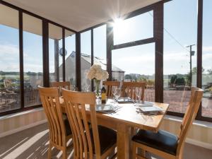 a dining room with a table and chairs and large windows at Hillend Farm House in Dalry