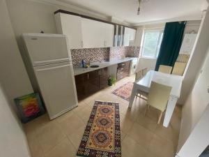 a kitchen with a white refrigerator and a table and chairs at Daily airport aparthotel in Taşoluk