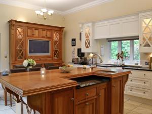 a kitchen with a large wooden island with a sink at The Coach House in Keswick +16 photos