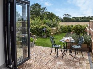 a patio with a table and chairs on a brick patio at Pightle Cottage in Poringland