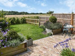 a garden with a table and some flowers at Pightle Cottage in Poringland