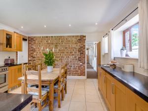 a kitchen with a wooden table and a brick wall at Beech Barns - Czu in Neatishead