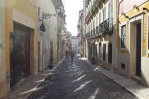 un homme se promenant dans une allée pavée avec des bâtiments dans l'établissement FADO Bairro Alto - SSs Apartments, à Lisbonne