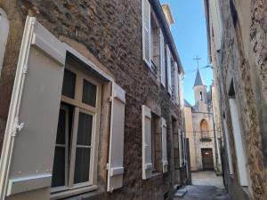 an alley with windows and a church in the background at Le logis de Presle in Avallon