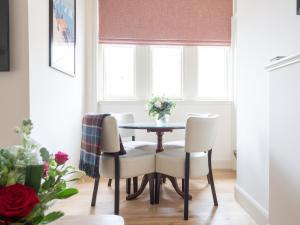 a dining room table with white chairs and a window at Tree House - Uk7556 in Inverness