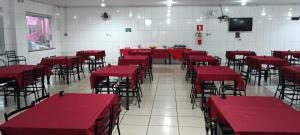 a room with red tables and chairs and a tv at Hotel Dom Mineiro in Curvelo