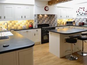 a large kitchen with white cabinets and black counter tops at Bram Crag Barn in Legburthwaite