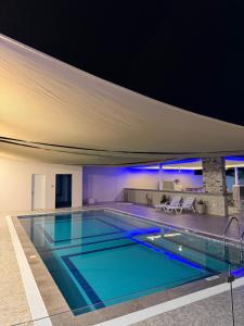a swimming pool in a house with blue lighting at Rovana Chalet in Barka