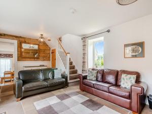 a living room with two leather couches and a staircase at Coltus Lands in Castleton