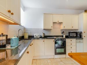 a kitchen with white cabinets and black appliances at Coltus Lands in Castleton