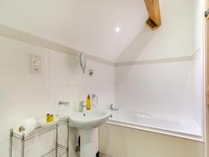 a white bathroom with a sink and a bath tub at Coltus Lands in Castleton