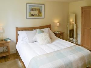 a bedroom with a white bed with two night stands at The Stables in Occold