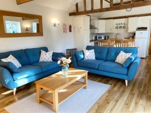 a living room with two blue couches and a table at The Stables in Occold