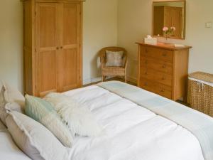 a large white bed in a bedroom with a dresser at The Stables in Occold