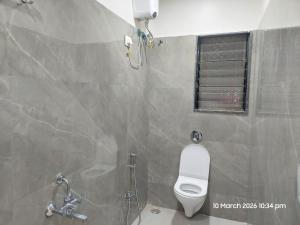 a bathroom with a toilet and a shower with a window at Vishal Lodge in Yermala