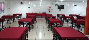 an empty room with red tables and chairs at Hotel Dom Mineiro in Curvelo