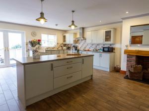 a large kitchen with white cabinets and a fireplace at Sycamore Cottage-Uk2785 in Penmaen-mawr +18 photos