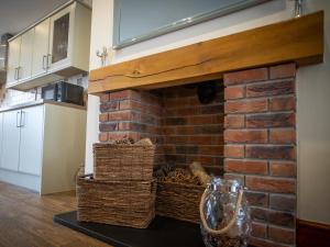 a brick fireplace in a kitchen with wicker baskets at Sycamore Cottage-Uk2785 in Penmaen-mawr