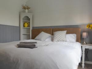 a bedroom with a white bed with pillows and a desk at Ponsford Ponds Jacks Shepherd Hut - Bcponhut in Cullompton