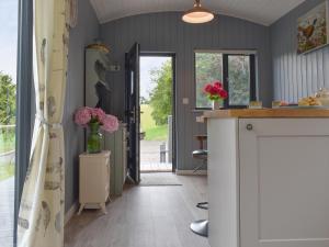 a kitchen with a counter and flowers in a room at Ponsford Ponds Jacks Shepherd Hut - Bcponhut in Cullompton +9 photos