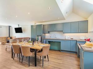 a kitchen with blue cabinets and a table with chairs at The Old Stables - Uk37000 in Ridlington +24 photos