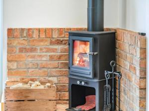 a wood stove in front of a brick wall at The Old Stables - Uk37000 in Ridlington