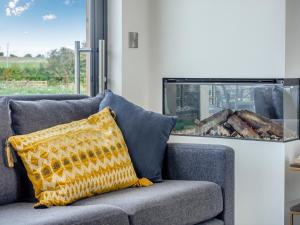 a couch with a yellow pillow sitting in front of a window at Buttercup Lodge - Uk36655 in Boothby Pagnell