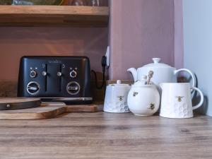 a counter with three tea cups and a toaster at Honey Cottage in Gargrave +17 photos