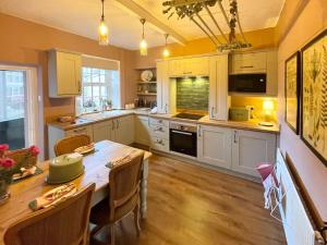 a kitchen with white cabinets and a wooden table at Honey Cottage in Gargrave